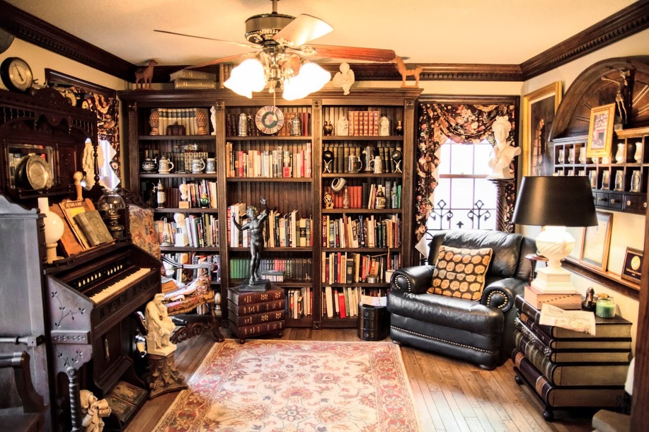 A cozy study featuring a large bookshelf filled with books, a comfortable armchair, and decorative artifacts.