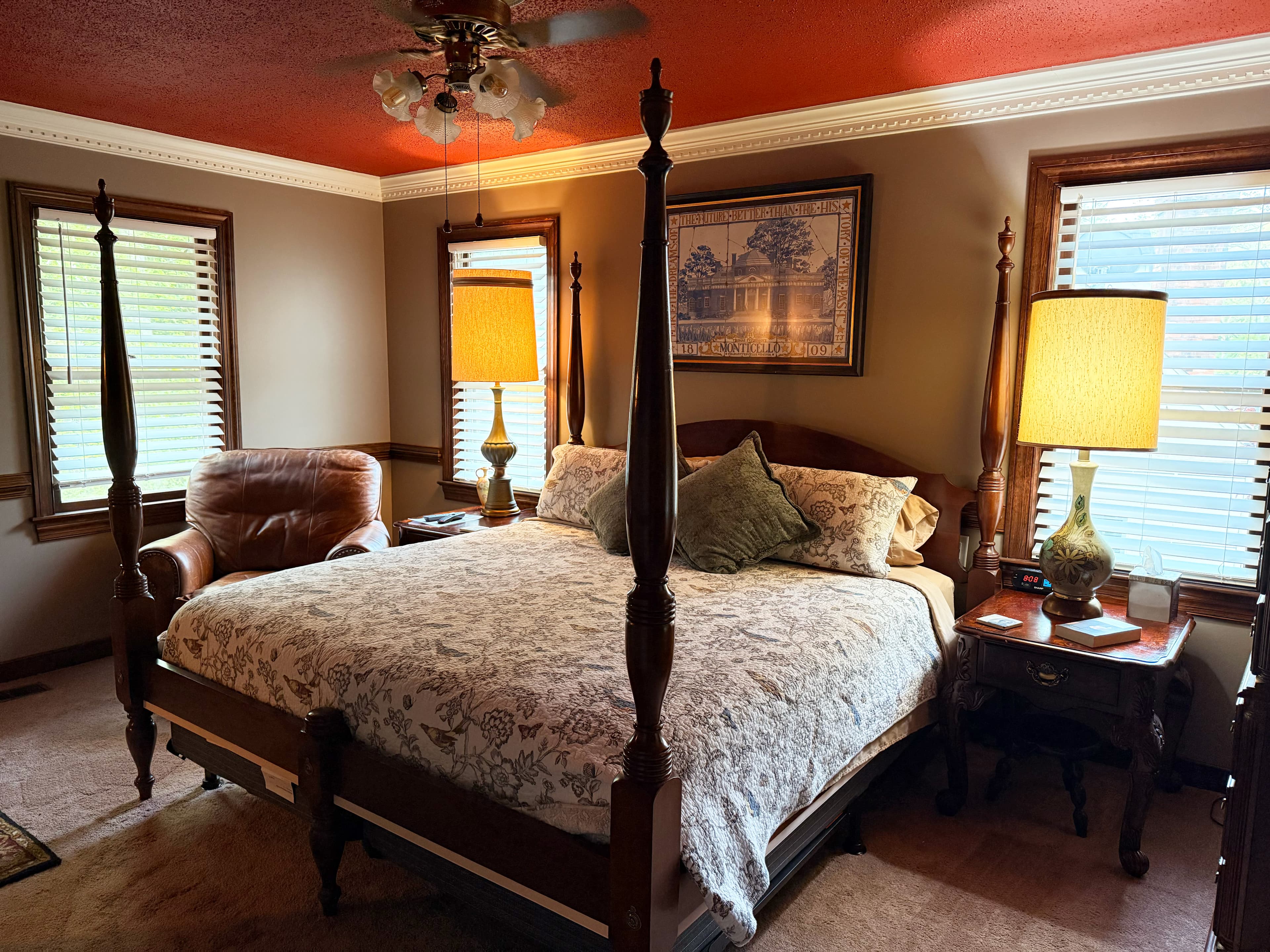 Cozy bedroom featuring a four-poster bed, armchair, and two lamps under a red ceiling.