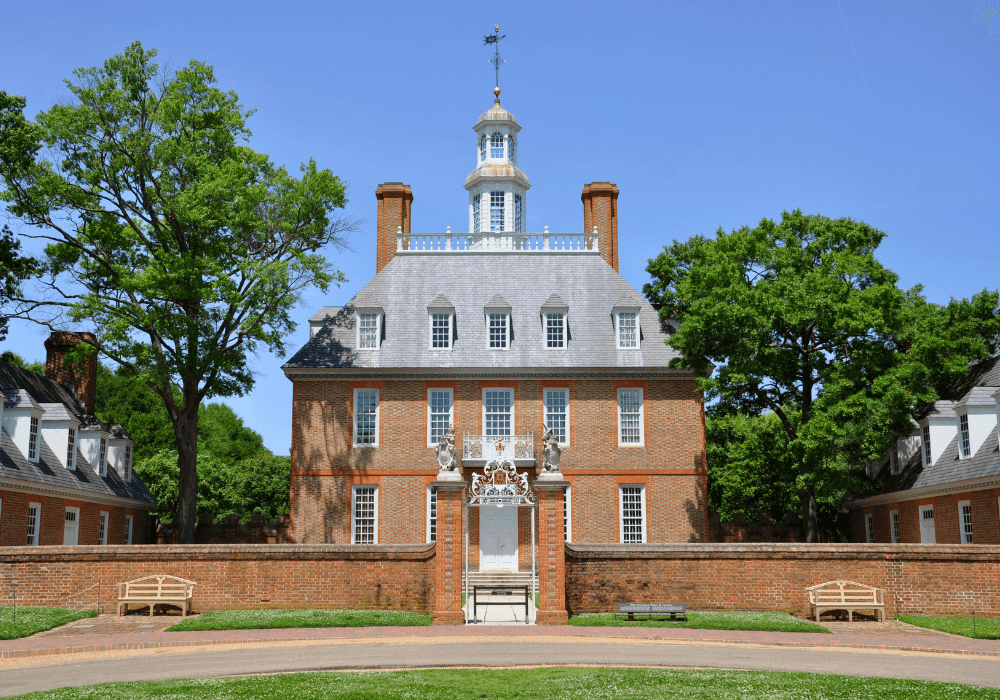 Historic brick building with a clock tower surrounded by trees and benches.