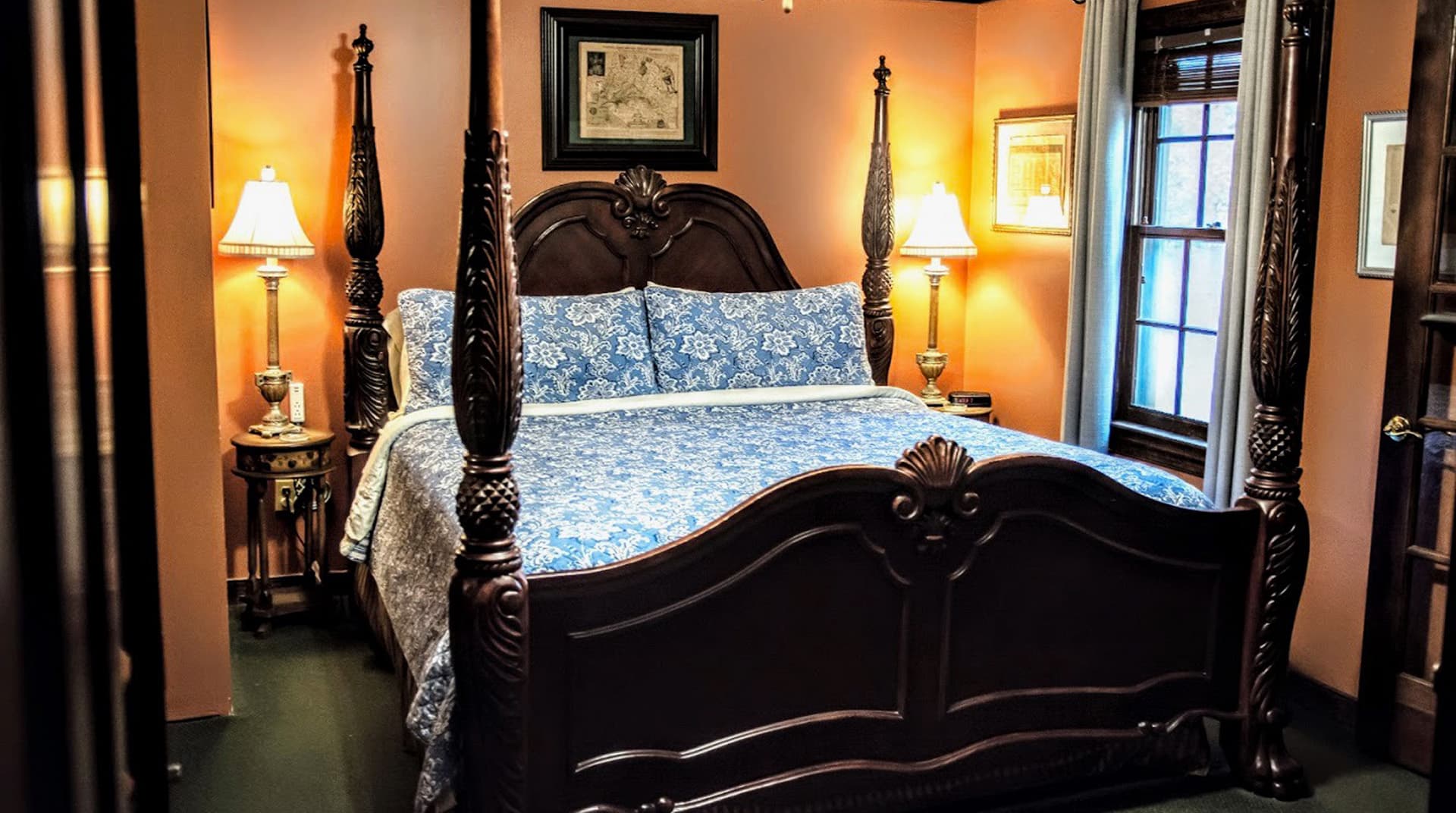 A beautifully decorated bedroom featuring an ornate four-poster bed with blue floral bedding and soft lamps.
