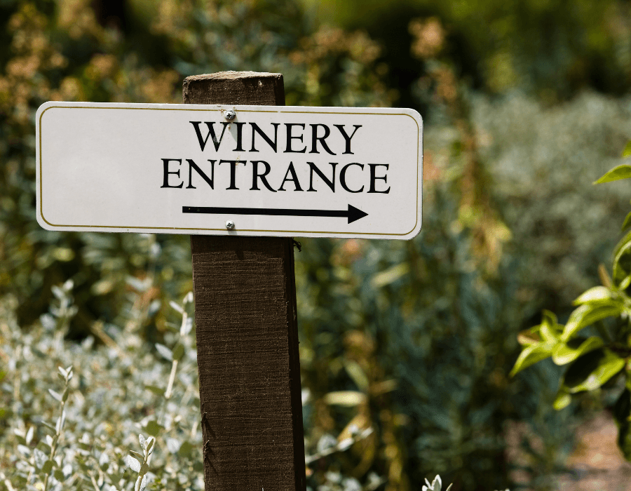 A sign pointing to the winery entrance with a leftward arrow.