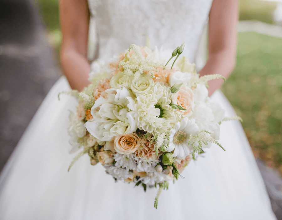A close-up of a bride holding a bouquet of pastel flowers.