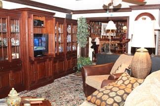 A warmly decorated living room featuring wooden furniture, a television, and decorative items.