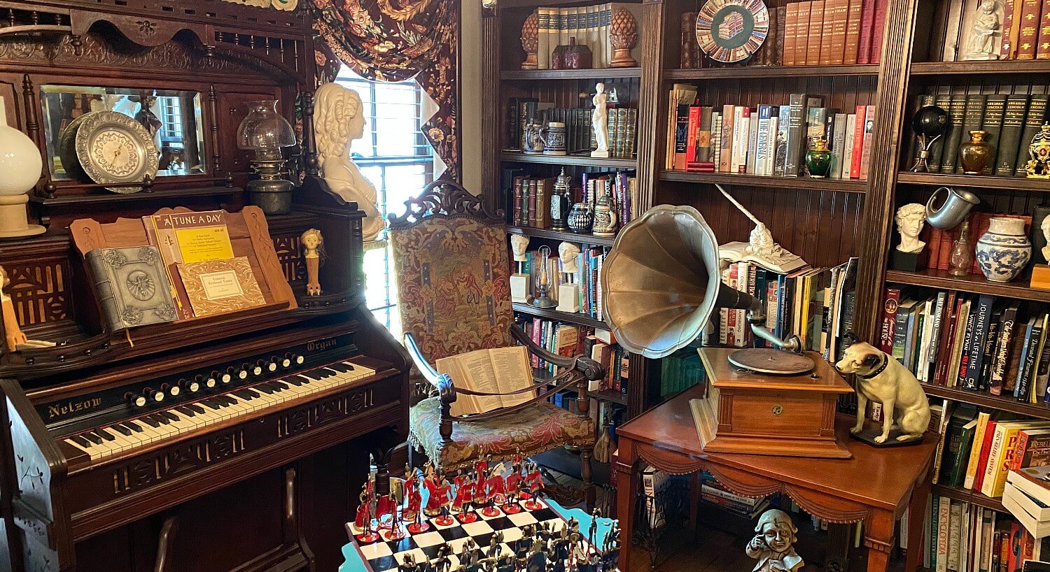 Study of an historic home with large bookshelves and many antiques including an organ and record player