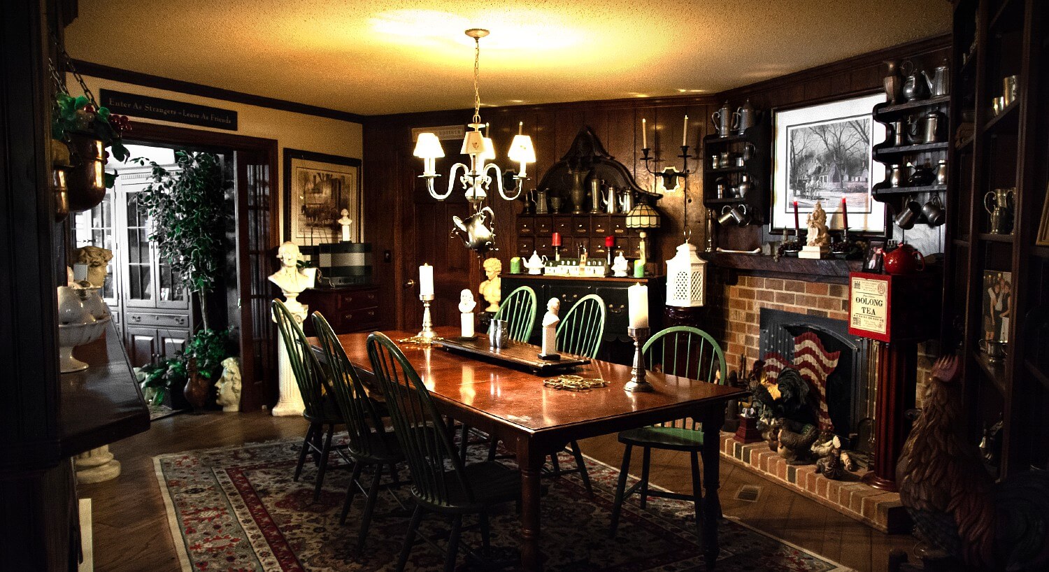 Dining room of a historic home with dark wood features, fireplace and antique decor