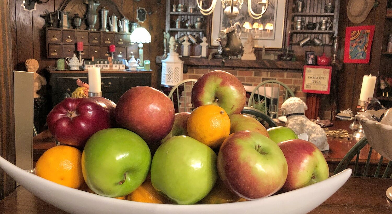 Bowl of red and green apples and oranges sitting on a counter in a dining room