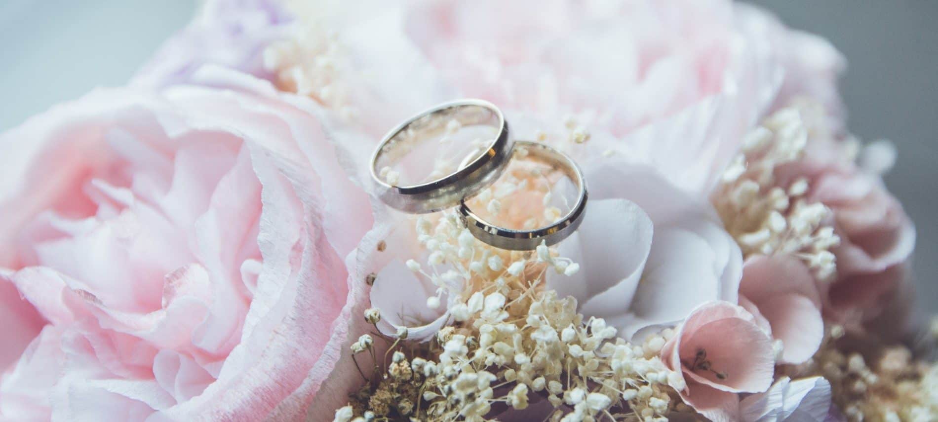 Two silver wedding bands sitting atop baby's breath and light pink flowers