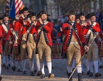 Group of men in civil war outfits walking down a street