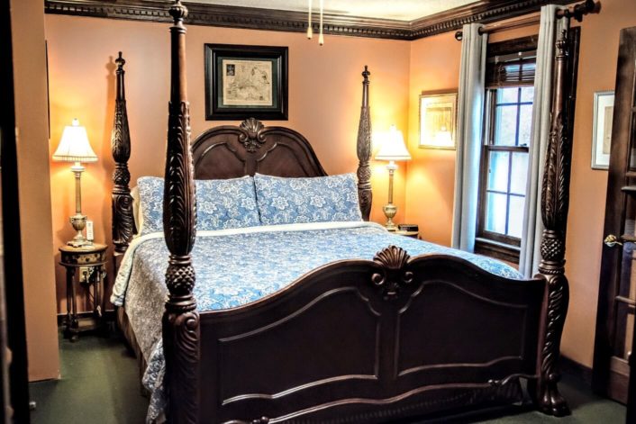 Bedroom with mahogany four poster bed, side tables with silver lamps and window