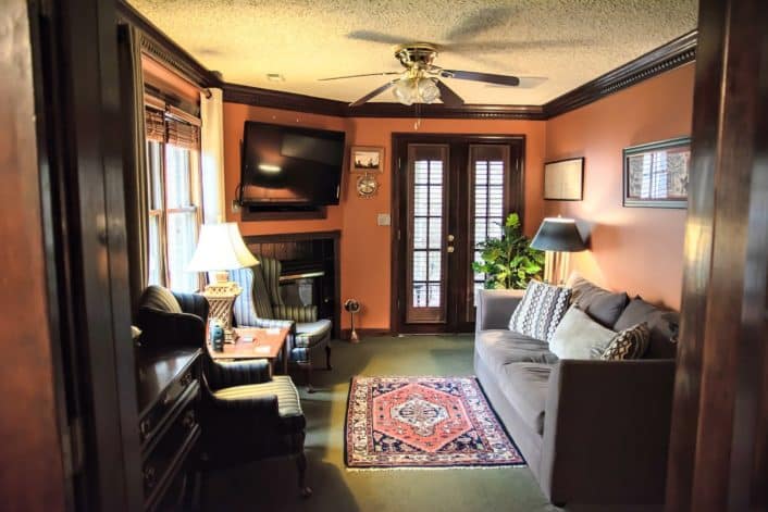 Side room with couch, sitting chairs, TV over fireplace and French doors