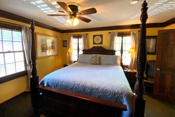 Elegant bedroom with dark wood accents, yellow walls and large four poster bed