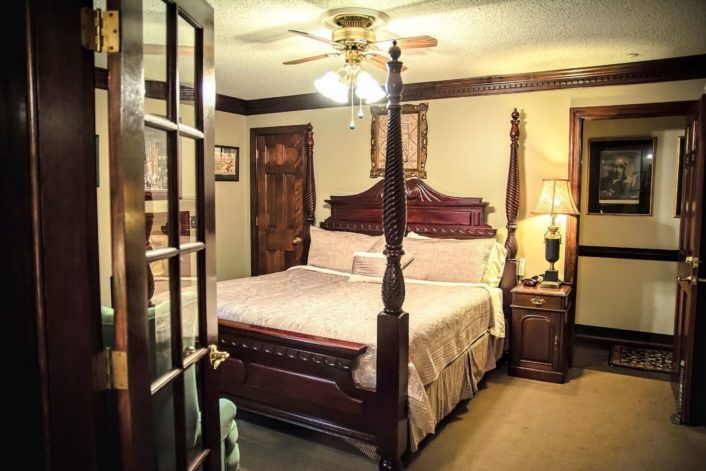 Bedroom with four poster bed, elegant linens and doorway into a hallway