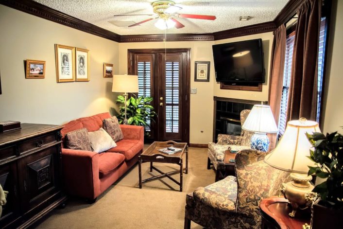 Sitting room with couch, wingback sitting chairs, TV over a fireplace and French doors