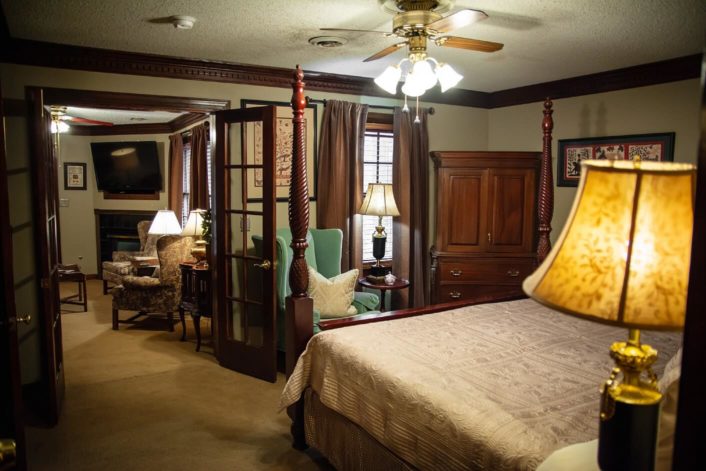 Spacious bedroom with four poster bed, armoire and doorway into a large sitting room