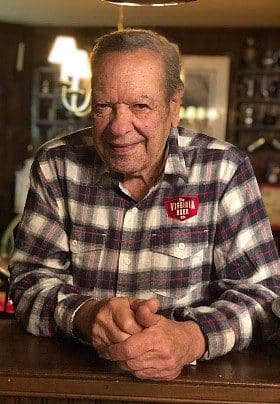 Older gentleman wearing a flannel shirt sitting at a counter in a home