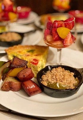 Breakfast plate with diced potatoes, slice of quiche and glass of strawberries