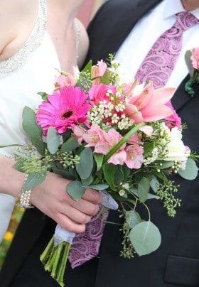 Woman in white dress holding bouquet of flowers next to a man in a dark suit